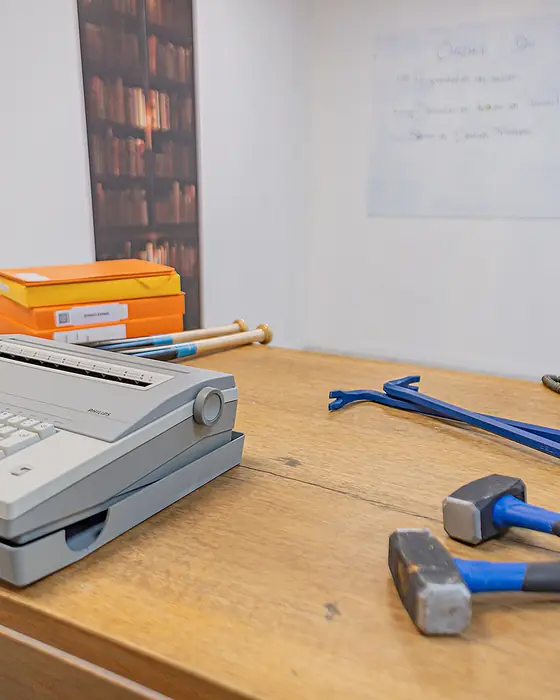 Machine à écrire, téléphone et masses posées sur la table de la salle bureau, avant la séance
