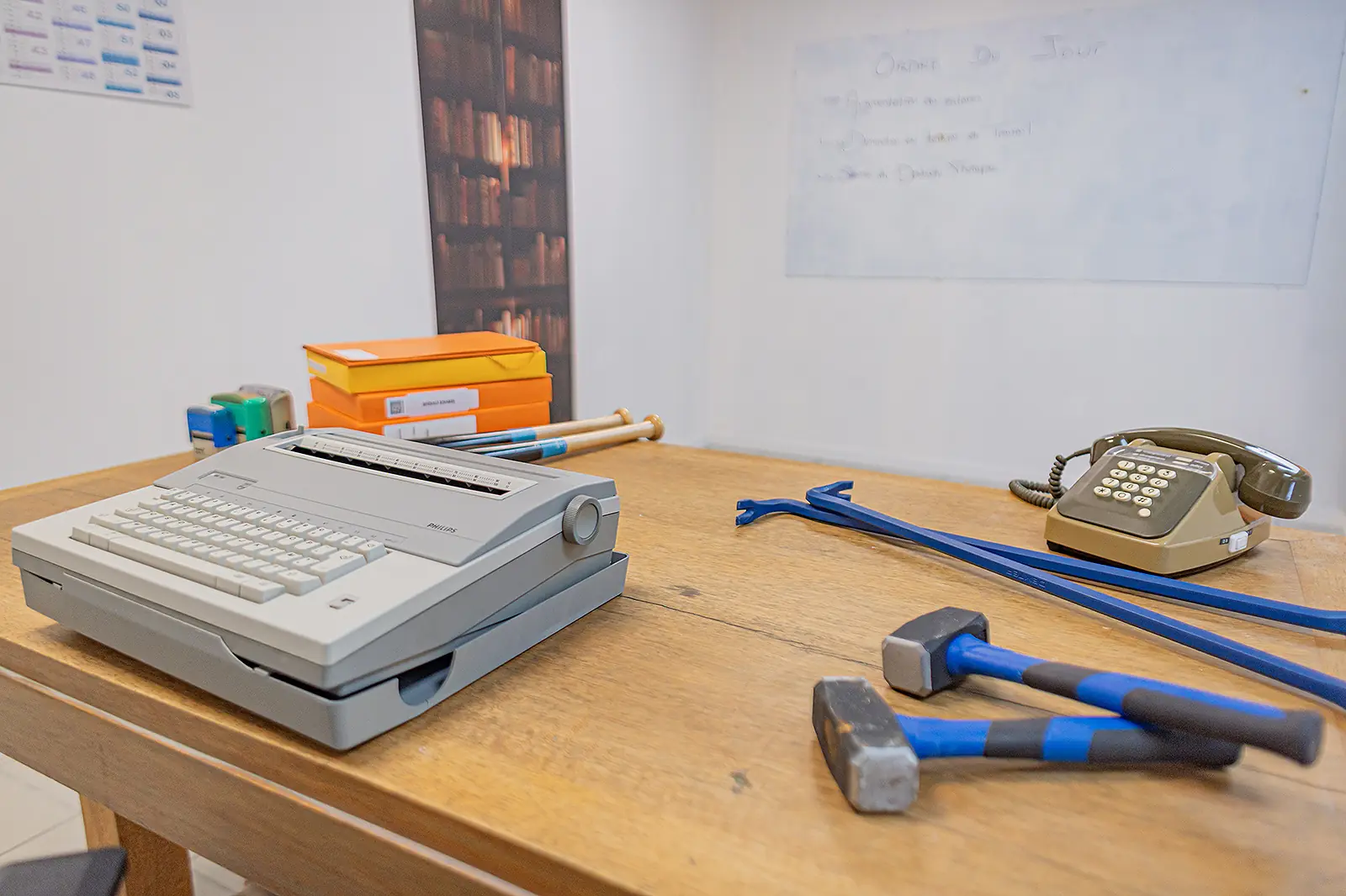 Le bureau de l'AtelierKS avant une séance : machine
à écrire Philips, téléphone à touches, deux masses et un
pied-de-biche posés sur le plateau, tableau blanc
« Ordre du jour » au mur