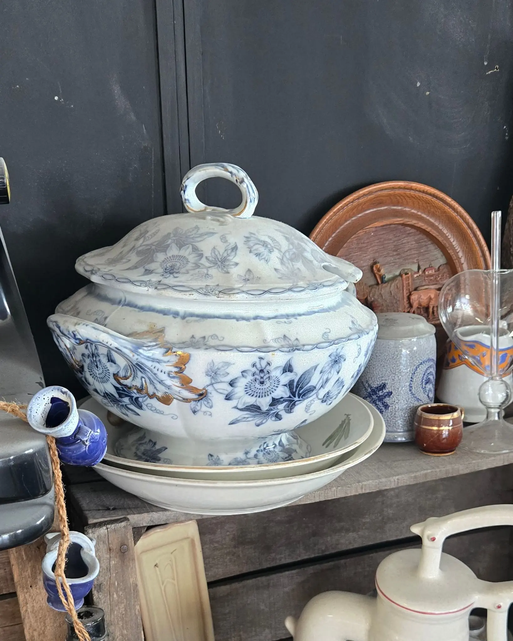 Soupière ancienne en faïence bleue posée sur deux assiettes, sur une étagère en bois de récupération