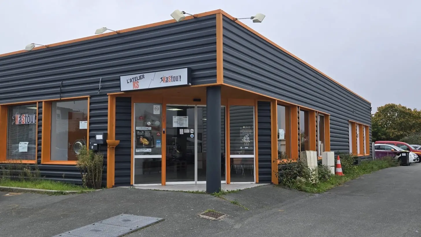 La façade de l'AtelierKS à La Rochelle : bardage anthracite et orange, enseigne L'ATELIER KS, parking devant l'entrée