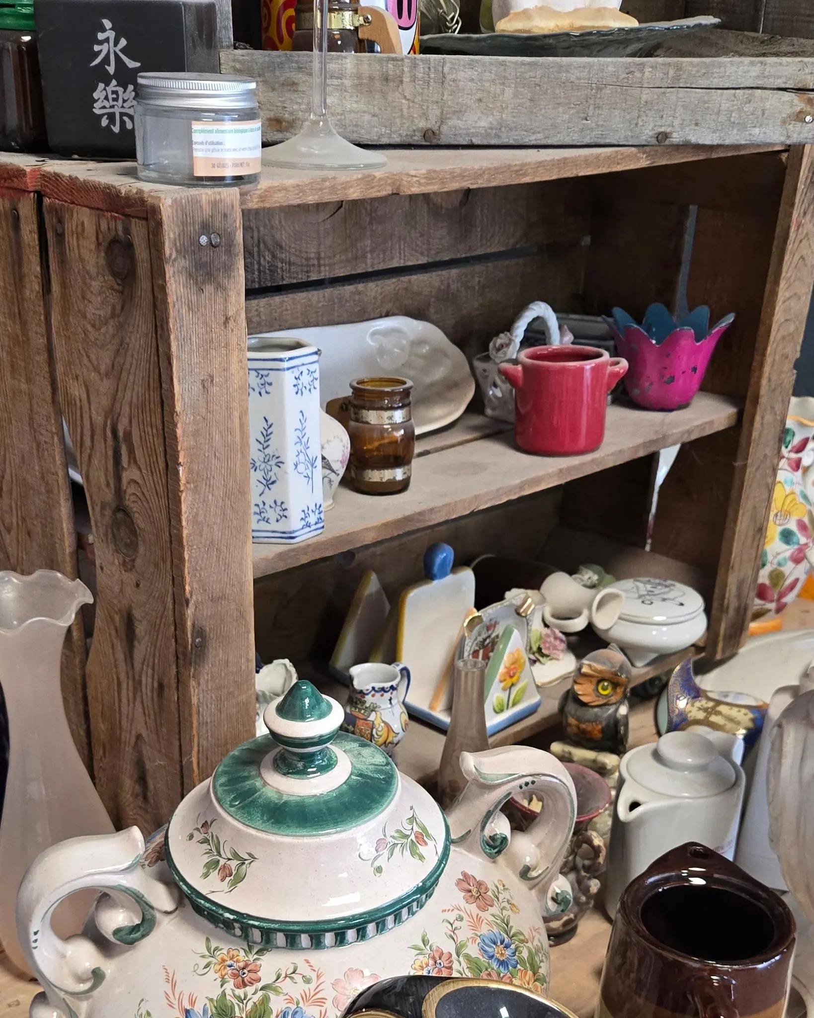 Théière à fleurs, pichets et pots en grès rangés dans des cagettes en bois avant une session
